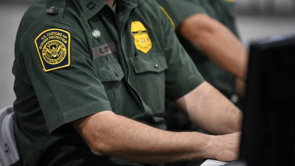 Agente de CBP revisando un dispositivo electrónico en la frontera de EE.UU.